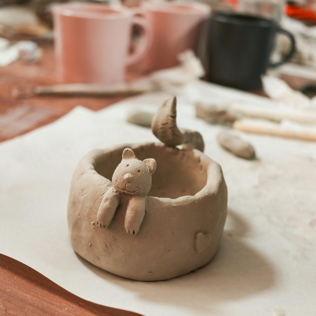 a photo of a bowl made out of clay with a clay bear poking its head out